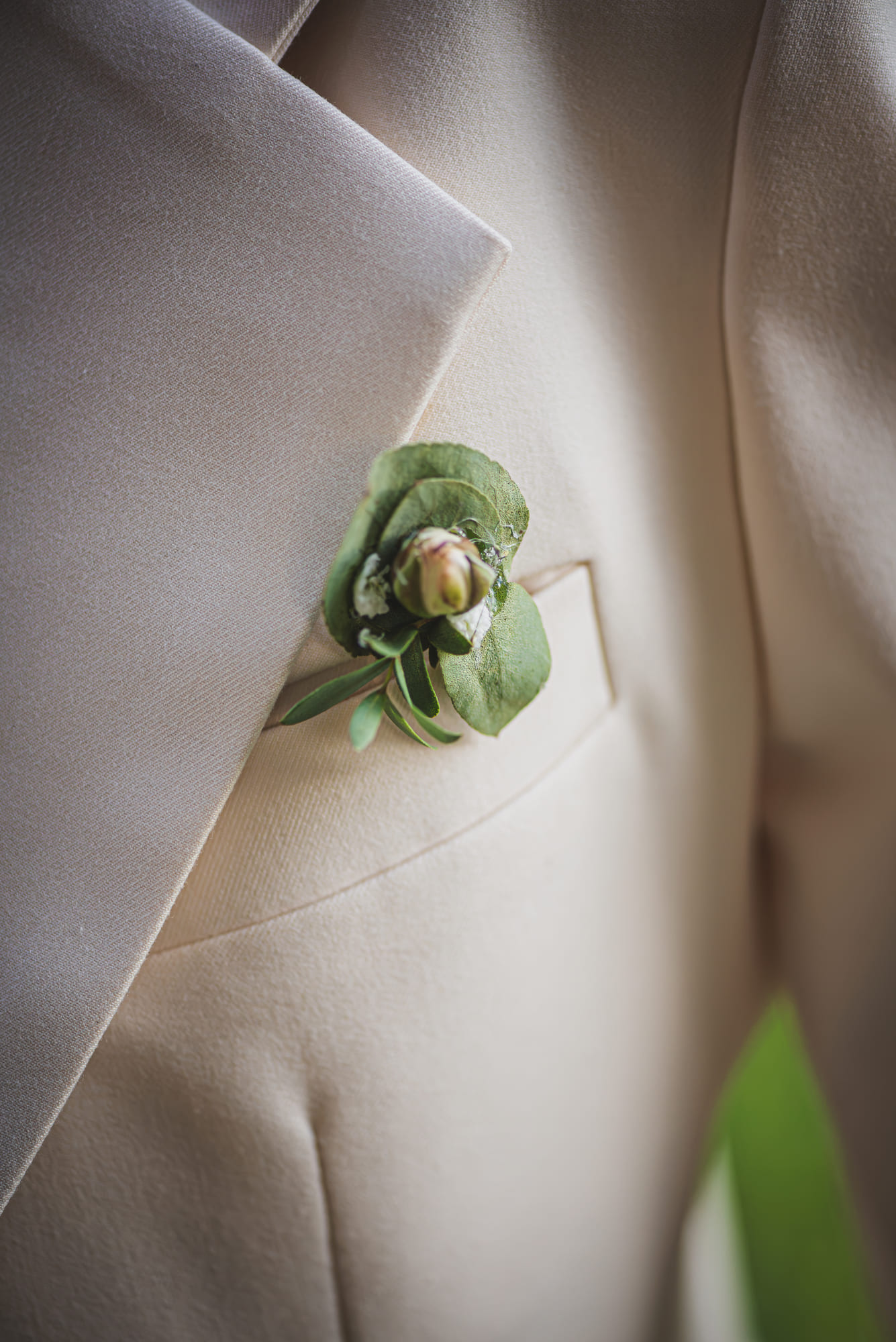 Boutonnière d’eucalyptus épinglée sur le costume crème d’Aurélieu