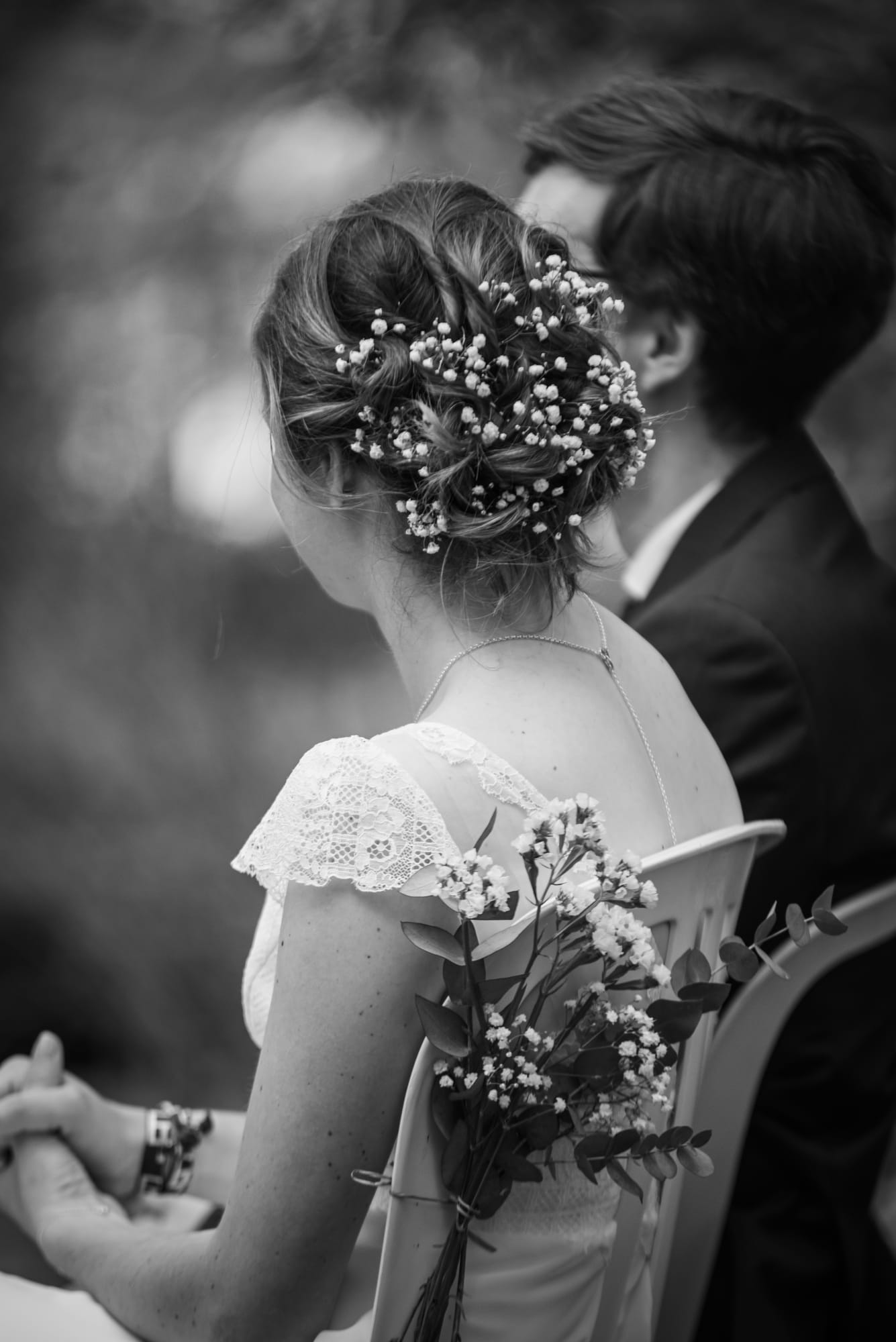 Laure de dos pendant la cérémonie laïque au Domaine de la Ruisselière, chignon orné de fleurs