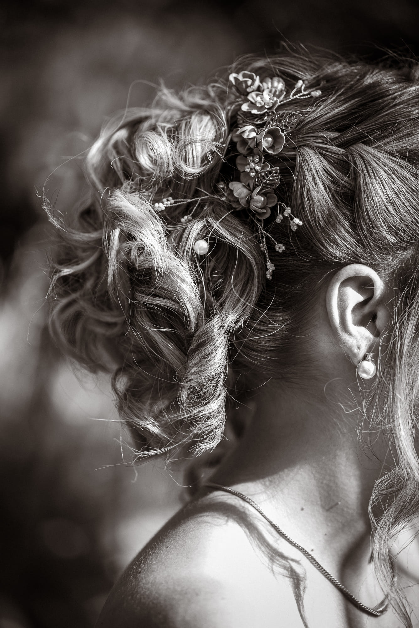 Détail de la coiffure de la mariée, tresse et bijou floral, en noir et blanc