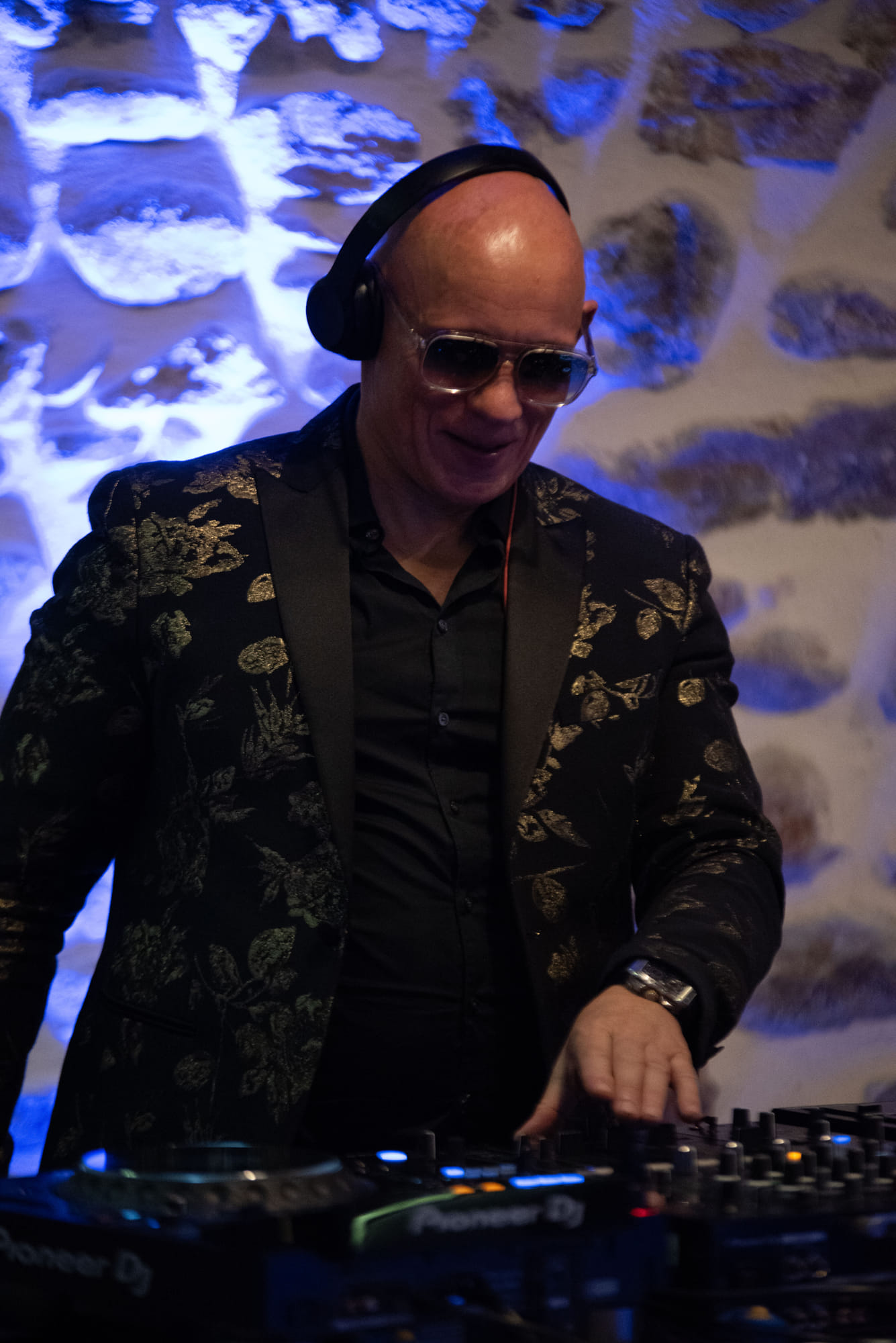DJ au platine pendant la soirée, lumière bleue sur un mur de pierre