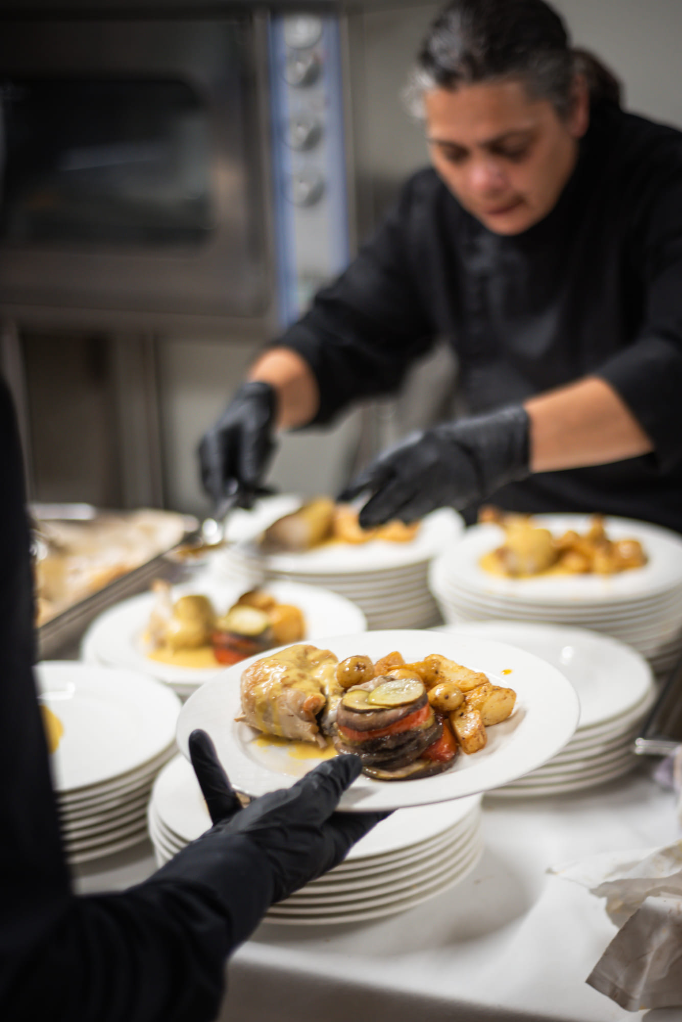 Assiette de réception dressée au premier plan, service en cuisine en arrière-plan