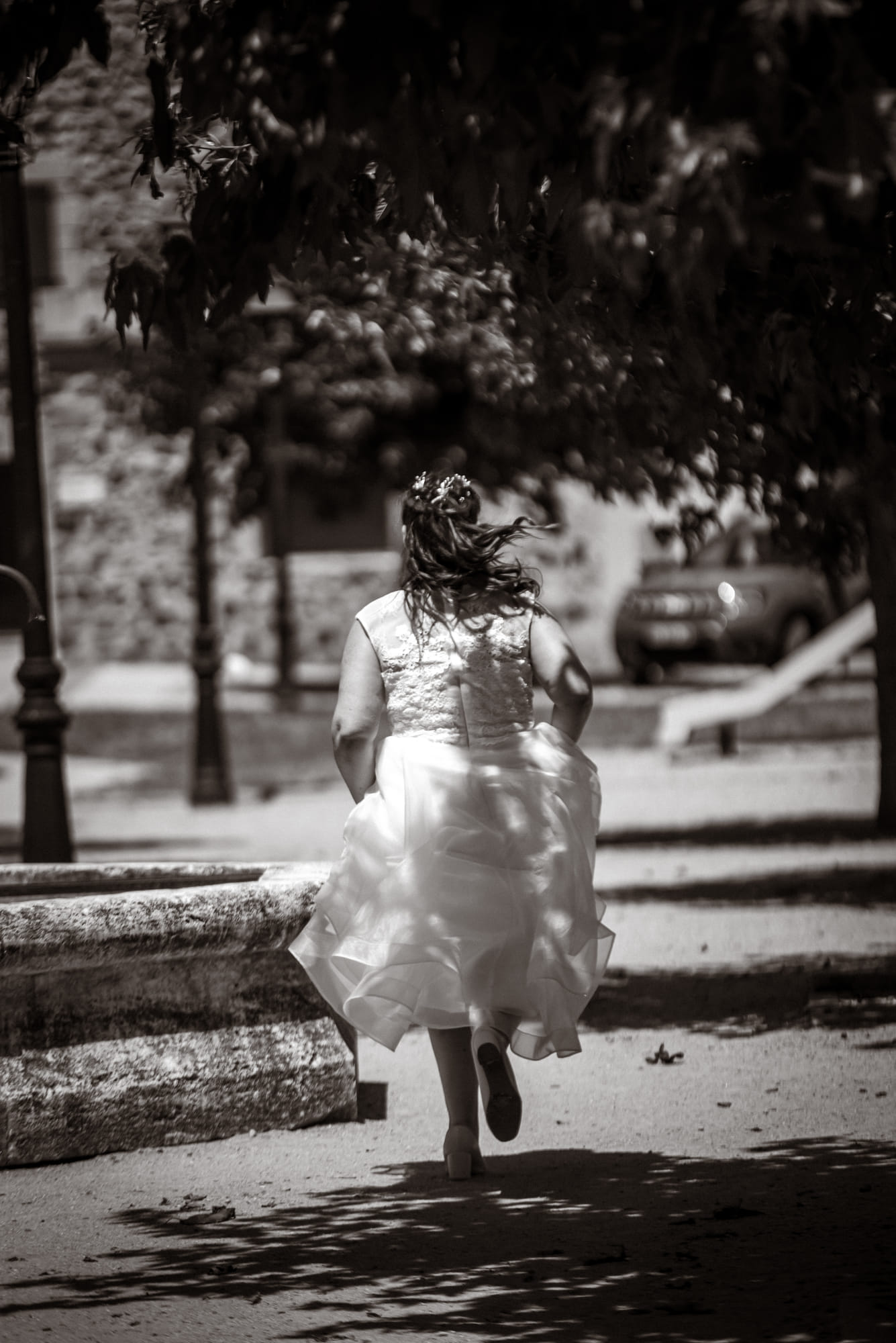 Enfant en robe claire courant dans une cour, saisie en noir et blanc