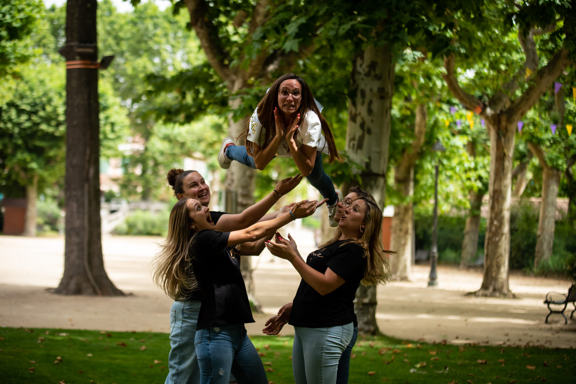 Amies lançant l’une d’elles en l’air dans un parc, pendant une célébration