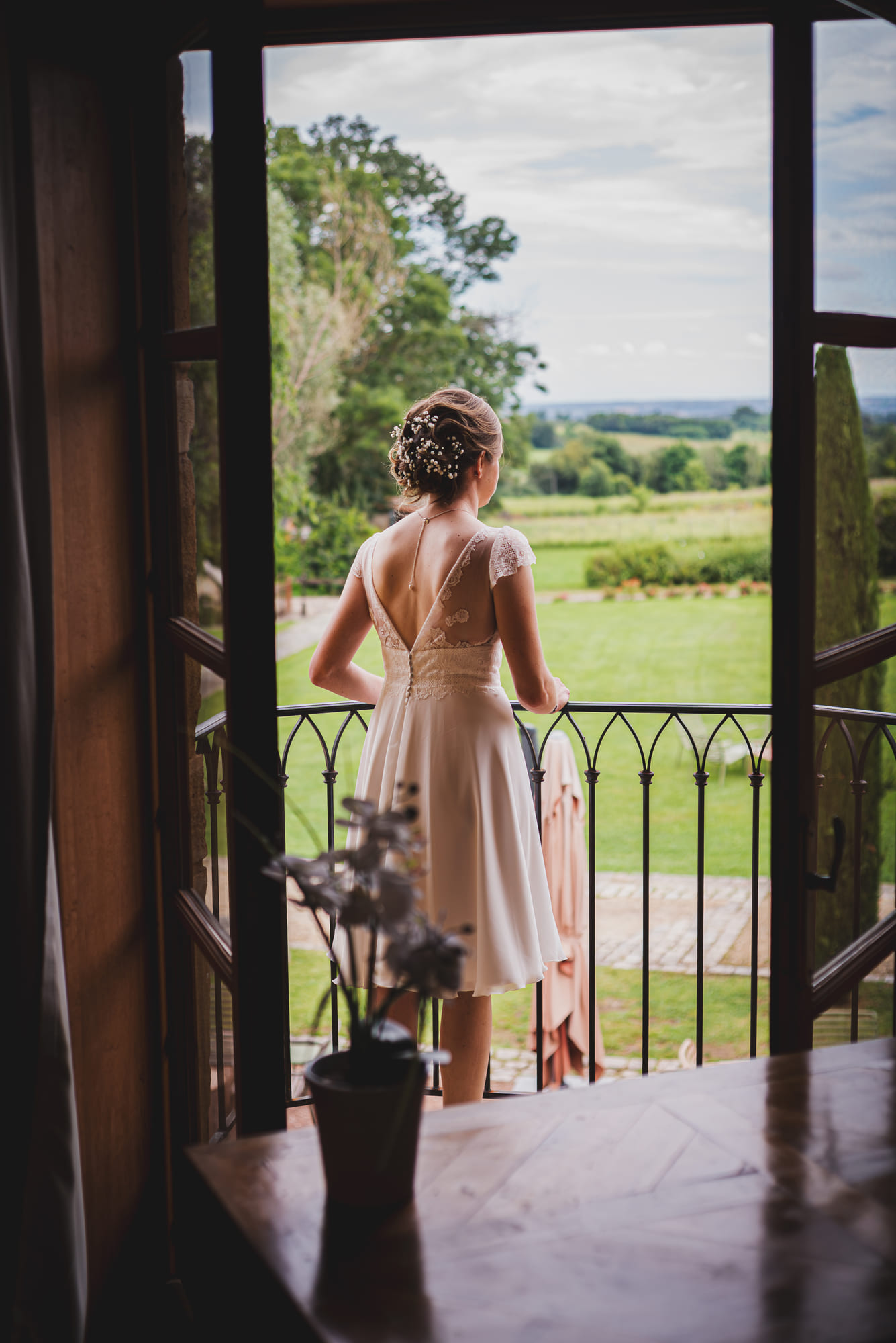Laure de dos sur un balcon du domaine, regardant les collines des Pierres Dorées