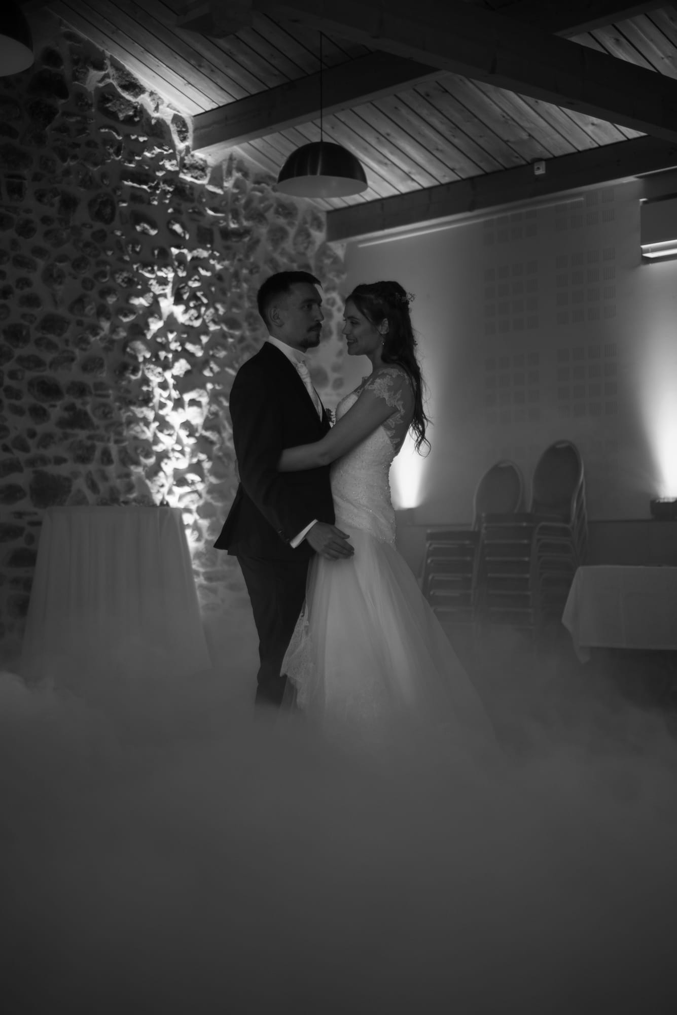 Mariés enlacés pour la première danse, dans la brume, en noir et blanc