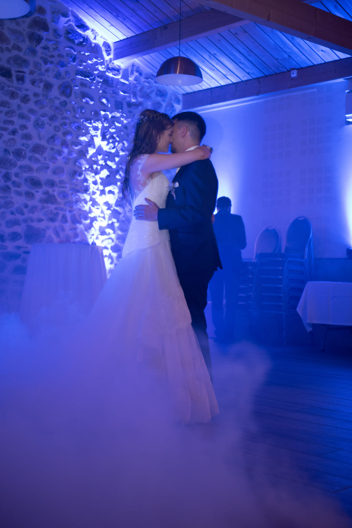 Première danse des mariés dans la brume, sous une lumière bleue