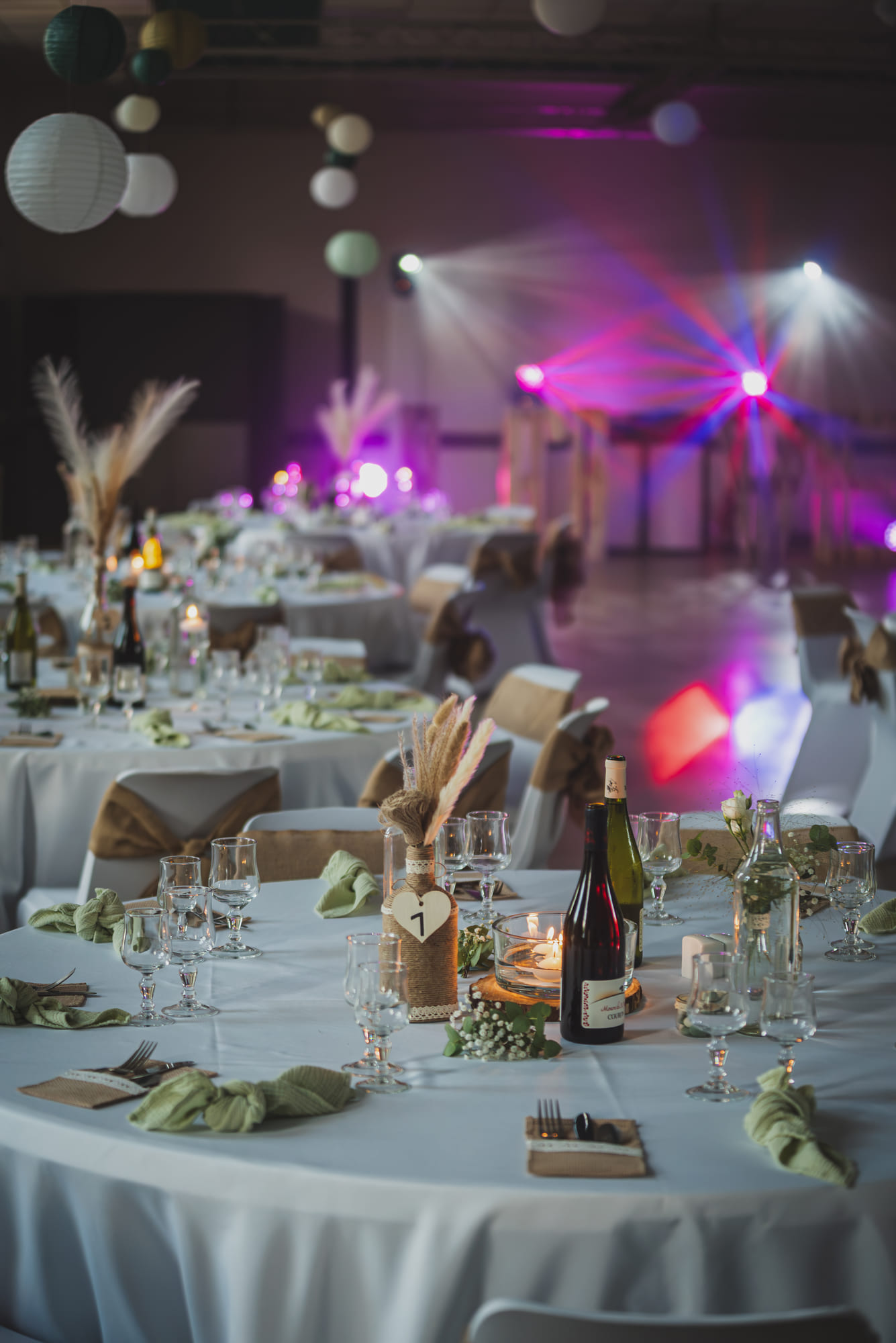 Tables de réception dressées, nappes blanches et centres de table, salle du mariage à Ucel